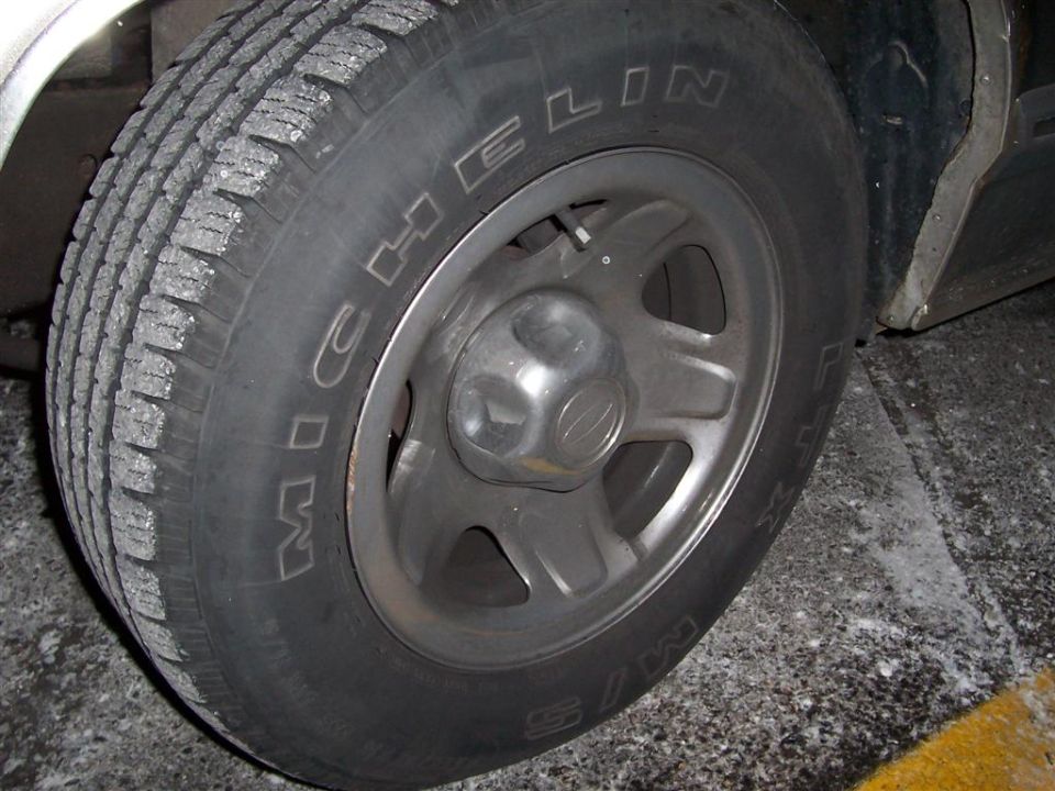 Michelin tire on a silver 5-spoke wheel, with some salt or ice on the tread