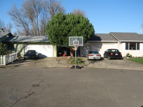1994 Ford Probe - A suburban scene with three cars parked in front of garages on a sunny day.