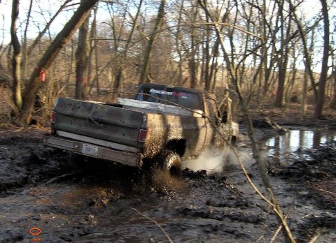 1976 GMC C/K Pickup - This pickup truck is struggling to get through a muddy, wooded terrain.