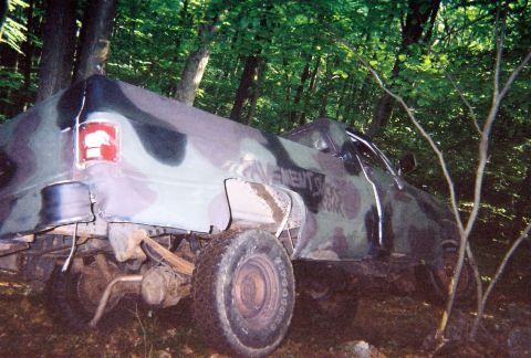 1976 GMC C/K Pickup - Camouflaged 1976 GMC C/K Pickup truck partially covered in woods.