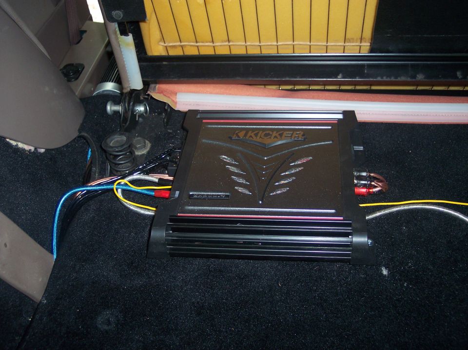 Black Kicker amplifier installed on black carpeted floor with wiring connected inside the Bronco