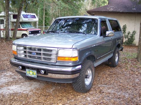 1996 Ford Bronco - This 1996 Ford Bronco is parked in a wooded area next to a house, with an RV visible in the background.