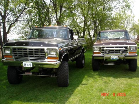 1979 Ford F-250 - Two Ford trucks, a lifted black F-250 and a brown F-250, are parked side-by-side on a grassy lawn.