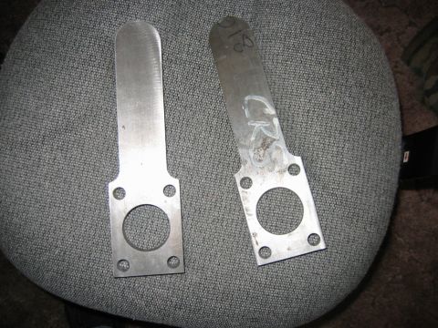 1992 Ford Mustang - Two metal brackets are shown, one with markings, resting on a textured surface.