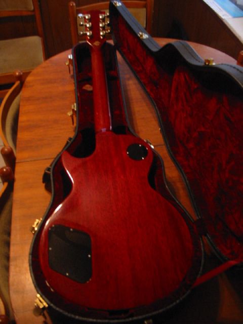 1989 Mazda MX-6 - Back of a red electric guitar lying in its open case on a wooden table.