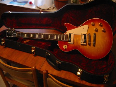 1989 Mazda MX-6 - A sunburst electric guitar rests in its plush-lined case on a wooden table.