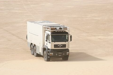 1993 Ford Bronco - A white MAN truck with a camper body navigates a sandy terrain.