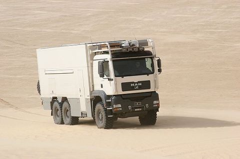 1993 Ford Bronco - A white MAN expedition truck with a large camper body is seen driving across sand dunes.