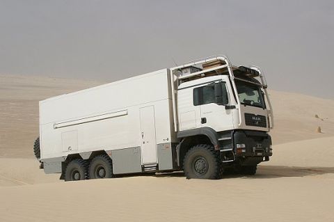 1993 Ford Bronco - A large, white expedition truck navigates through a sandy desert landscape.