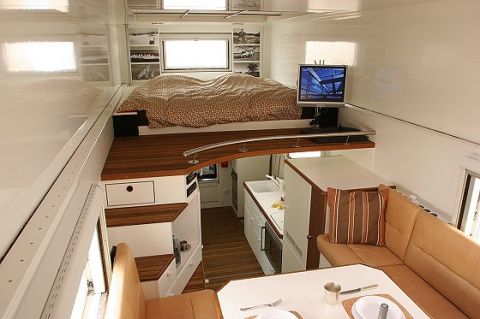 1993 Ford Bronco - This RV interior features a raised bed, a compact kitchen, and a comfortable seating area with a table.