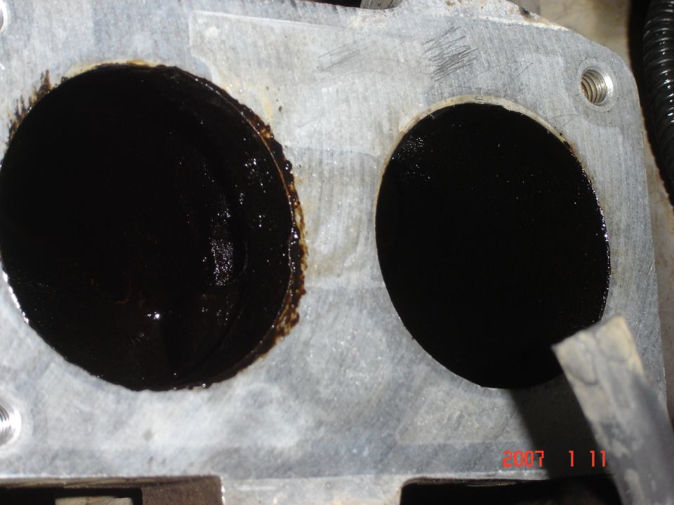 Aluminum twin-bore intake flange caked with black carbon sludge