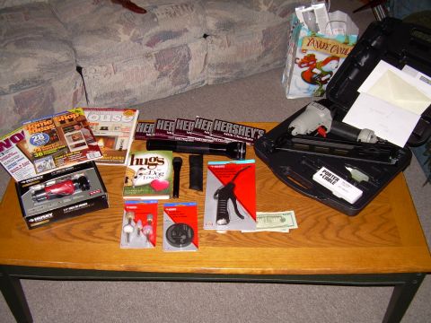1966 Land Rover Discovery - A collection of items including magazines, candy, tools, and a nail gun are spread across a wooden coffee table.