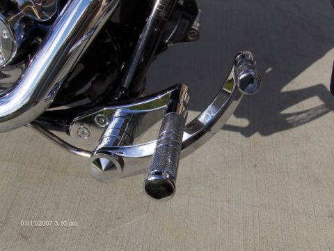 2004 Ford Crown Victoria - Close-up view of chrome motorcycle footpegs and exhaust pipes.