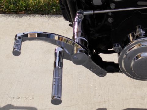 2004 Ford Crown Victoria - Close-up view of chrome motorcycle foot pegs and associated linkage, with a timestamp visible in the lower left corner.