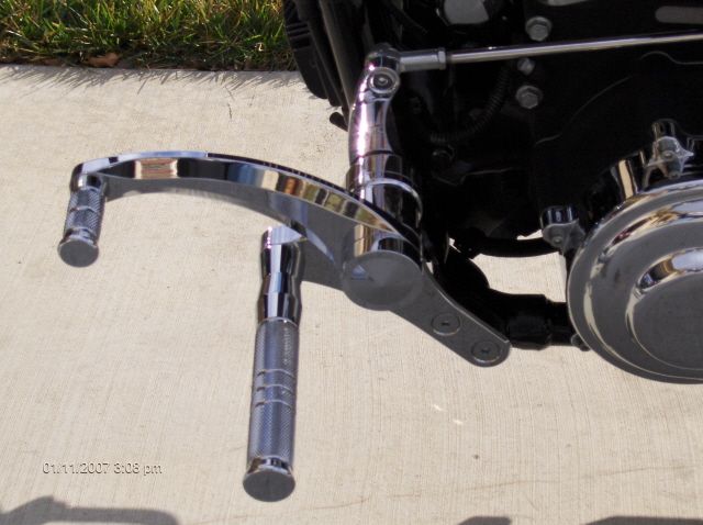 Chrome motorcycle foot pegs and linkage on a concrete surface