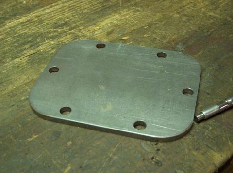 1991 Ford Bronco - A metal plate with six holes is shown on a wooden workbench.