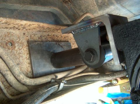 1991 Ford Bronco - Close-up of a custom suspension bracket, likely an aftermarket modification, attached to a heavily rusted vehicle frame.