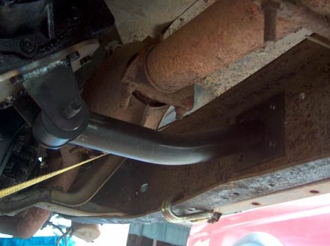 1991 Ford Bronco - A close-up view of the undercarriage reveals a rusty exhaust system and a dark suspension part.