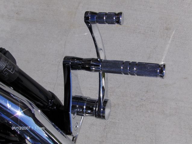 Chrome motorcycle foot controls with textured grips mounted on a black frame