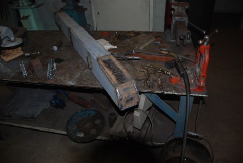 1996 Ford Bronco - A custom metal part sits on a workbench surrounded by welding equipment and tools.