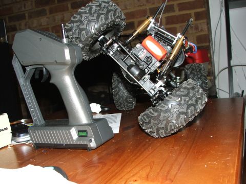 1996 Ford Bronco - A remote control monster truck chassis and its controller sit on a wooden surface.