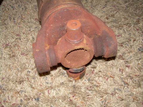 1988 Ford Bronco - Close-up of a heavily rusted driveshaft universal joint resting on a carpeted surface.