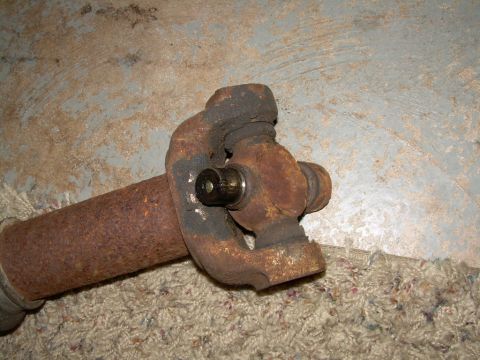 1988 Ford Bronco - A close-up view of a corroded driveshaft U-joint, likely removed from a vehicle for repair or replacement.