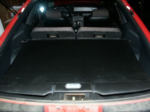 1990 Ford Mustang - View of the interior of a red car, focusing on the trunk area and rear seating.