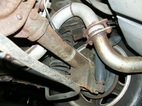 1990 Ford Mustang - The rear suspension and exhaust system of a vehicle are shown, with visible rust on the components.