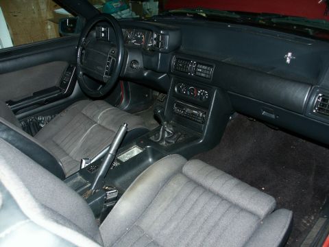 1990 Ford Mustang - The interior of a 1990 Ford Mustang features a manual transmission, cloth seats, and a dashboard with analog gauges.