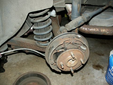 1990 Ford Mustang - Close-up view of a vehicle's rear drum brake assembly, showing suspension components and brake hardware.