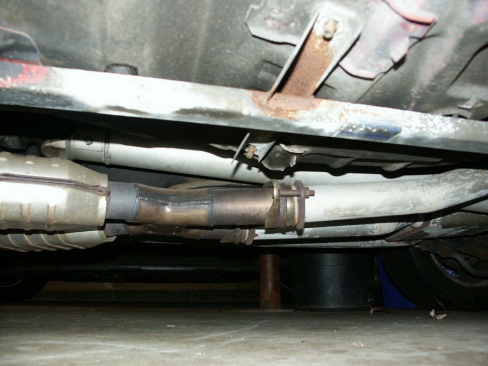 Underside view of a car's exhaust system with catalytic converter and muffler