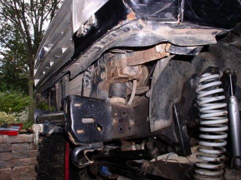 1991 Ford Bronco - Close-up view of the front suspension and bumper assembly of a black vehicle, showing signs of wear and modification.