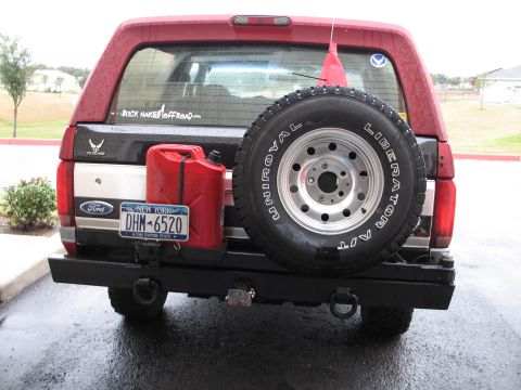 1995 Ford Bronco - The rear of a red and black Ford Bronco is shown with a spare tire mounted on the back, a red gas can, and a New York license plate.