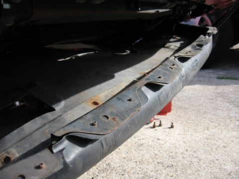 1991 Mitsubishi 3000GT - Close-up of a rusty car bumper reinforcement bar, likely undergoing repair or replacement.