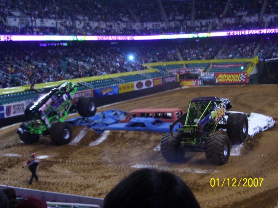 Monster trucks Grave Digger and another truck in a stadium arena with spectators