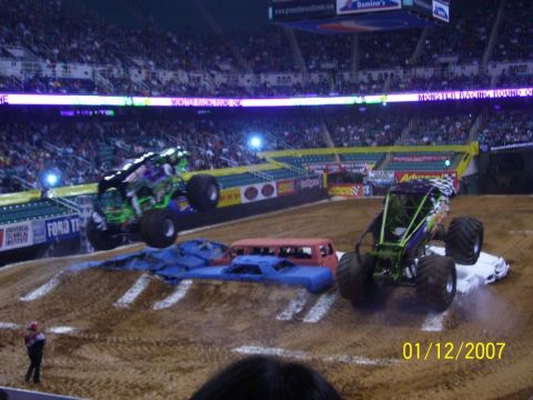 1993 Ford Bronco - Monster trucks perform stunts in an arena, crushing cars as part of the show.