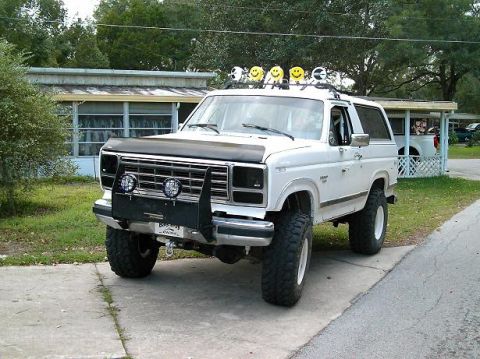 1986 Ford Bronco - White Ford Bronco with off-road modifications parked on a driveway.