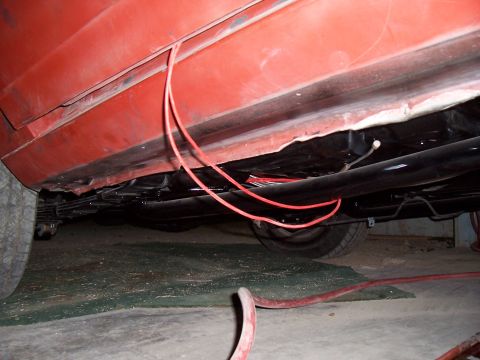 1979 Chevrolet Camaro - A low-angle view of the underside of a red vehicle, revealing exposed wiring and suspension parts.