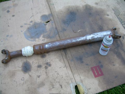 1988 Ford Bronco - A driveshaft is shown on cardboard next to a can of Rust-Oleum primer.