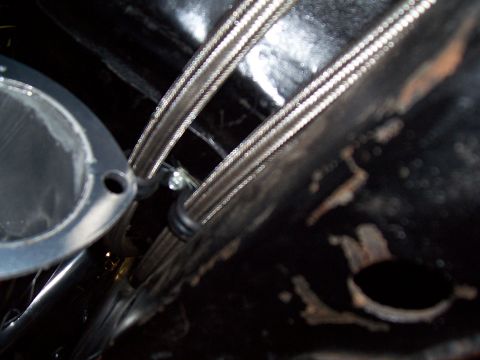 1979 Chevrolet Camaro - Close-up view of braided metal hoses and a metal flange on the underside of a vehicle.