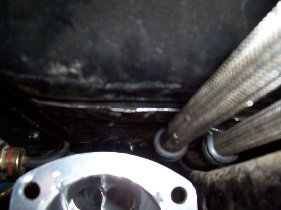 Close-up of braided stainless lines and polished aluminum flange under a vehicle