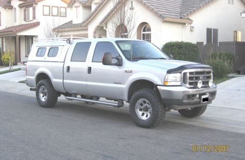 2004 Ford F-250 - This silver 2004 Ford F-250 pickup truck is equipped with a camper shell and roof rack.