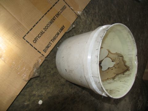 1978 Ford Bronco - A cardboard box and a bucket are on a concrete floor, with text visible on the box.