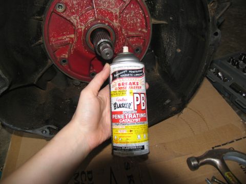 1978 Ford Bronco - A can of PB Blaster penetrating oil is held near a vehicle's transmission housing, suggesting maintenance or repair work.