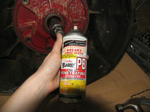 1978 Ford Bronco - A can of PB Blaster penetrating catalyst is held near a vehicle transmission part, suggesting maintenance or repair.