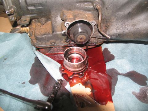 1978 Ford Bronco - A transmission part is removed, with red fluid spilled on shop towels and a socket wrench.