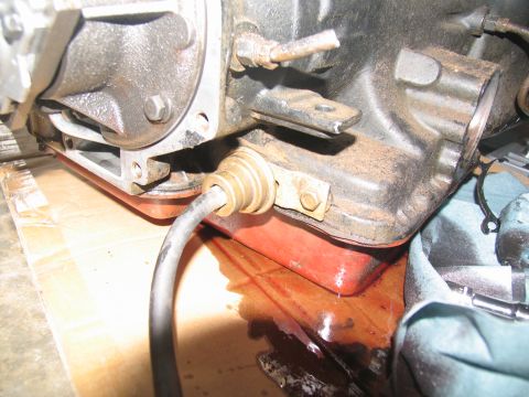 1978 Ford Bronco - A close-up view of a leaking transmission pan with a red gasket and fluid spill.