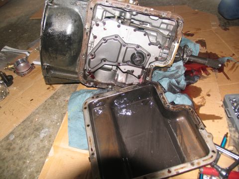 1978 Ford Bronco - A transmission pan, removed from the main body, reveals dark fluid and internal workings.