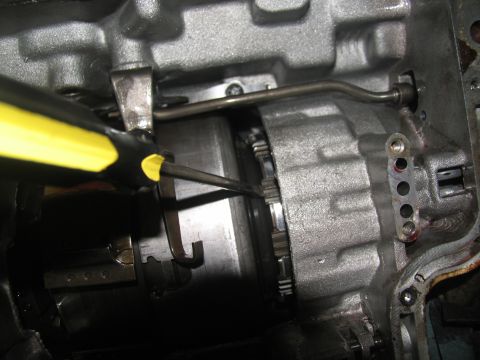 1978 Ford Bronco - A screwdriver is used to manipulate a part within a transmission assembly.